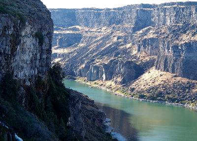 [Foreground canyon wall is in shadow while the other side is in full sun. Rockslides and intermediate levels of the canyon wall provide a gradual slope to the river in several places.]